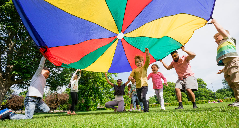 Children playing with a parachute at school during pe in the North East of England. A boy is running underneath it.