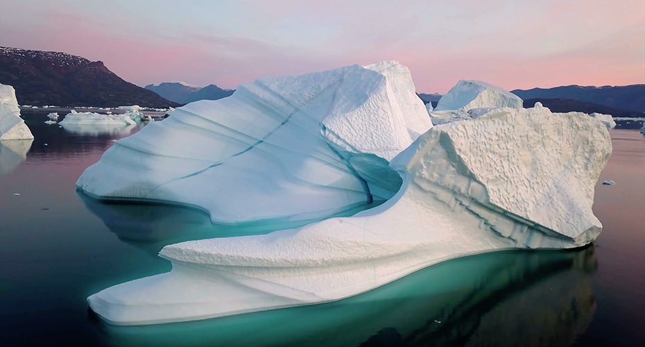 An iceburg at sunset in a serene sea.