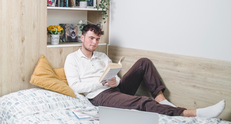 A student reading on his bed