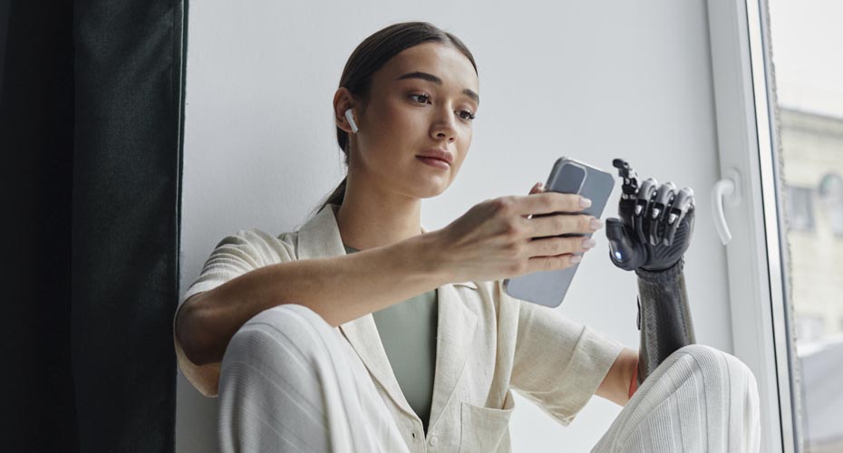 Young woman with prosthetic arm looking at a mobile phone