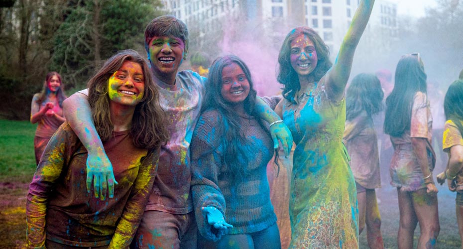 A group of students covered in brightly coloured powder at the Holi celebrations on campus