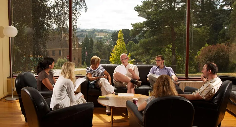 A group of university postgraduate students seated at a table, actively participating in a reading group discussion.