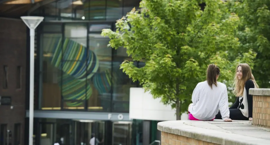 Two students sitting outside the forum at streatham campus.