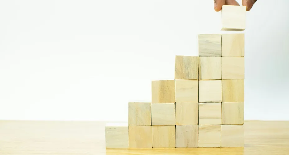 An individual is engaged in stacking wooden blocks, demonstrating skill in creating a stable structure.